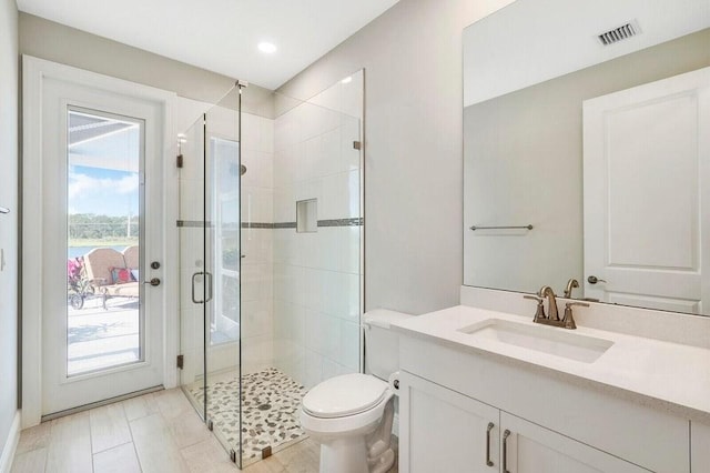 bathroom featuring vanity, an enclosed shower, and toilet