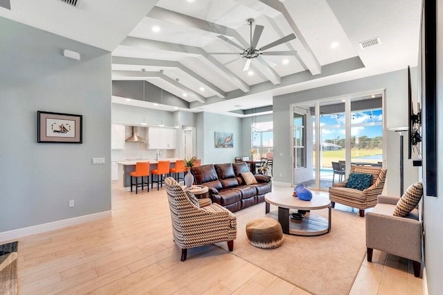 living room featuring lofted ceiling with beams, ceiling fan, and light hardwood / wood-style flooring