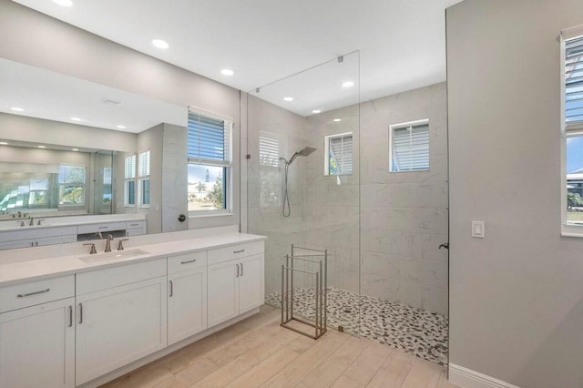 bathroom featuring vanity, a tile shower, and wood-type flooring