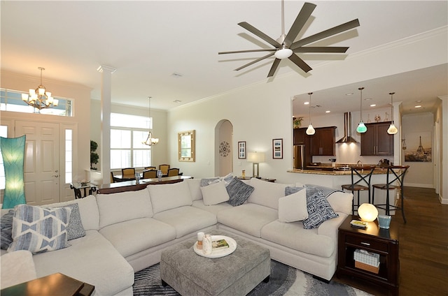 living room featuring dark hardwood / wood-style floors, ceiling fan with notable chandelier, and crown molding