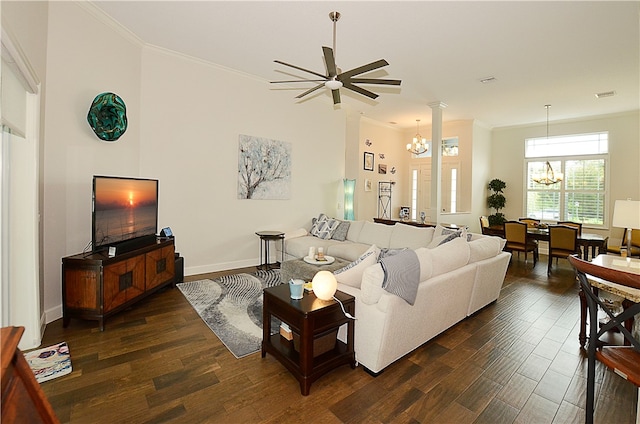 living room featuring dark wood-type flooring, ceiling fan with notable chandelier, crown molding, and decorative columns