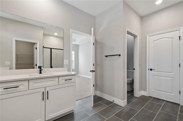 bathroom featuring tile patterned flooring, vanity, a shower with shower door, and toilet