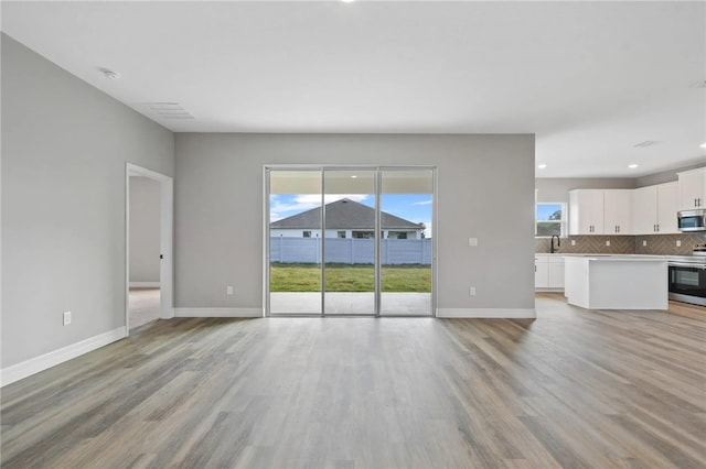 unfurnished living room with light hardwood / wood-style flooring and a wealth of natural light