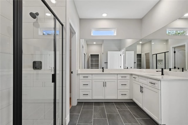 bathroom with a shower with door, vanity, and tile patterned flooring