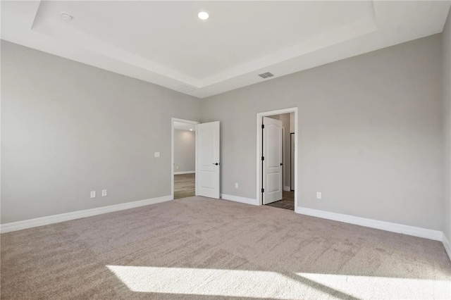 unfurnished bedroom featuring dark carpet and a tray ceiling