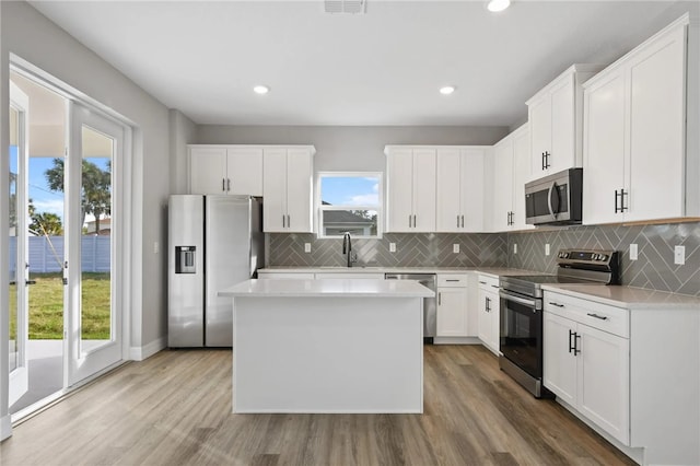 kitchen featuring a wealth of natural light, a kitchen island, white cabinets, and appliances with stainless steel finishes