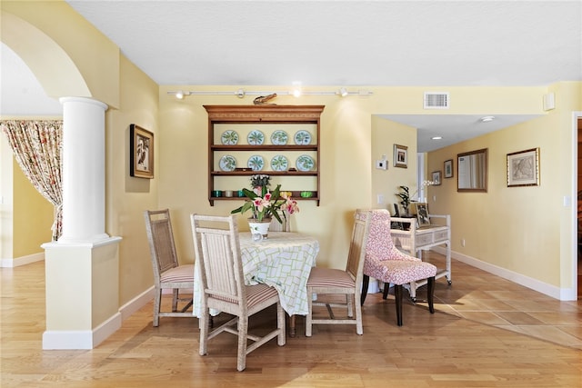 dining area featuring light hardwood / wood-style flooring and decorative columns