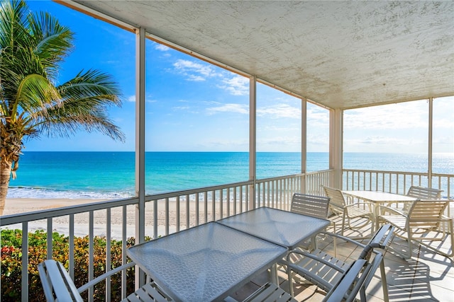 unfurnished sunroom featuring a beach view and a water view