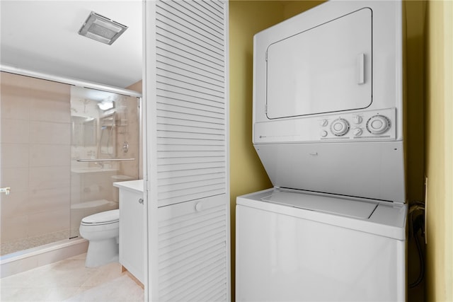 laundry room featuring light tile patterned floors and stacked washer / drying machine