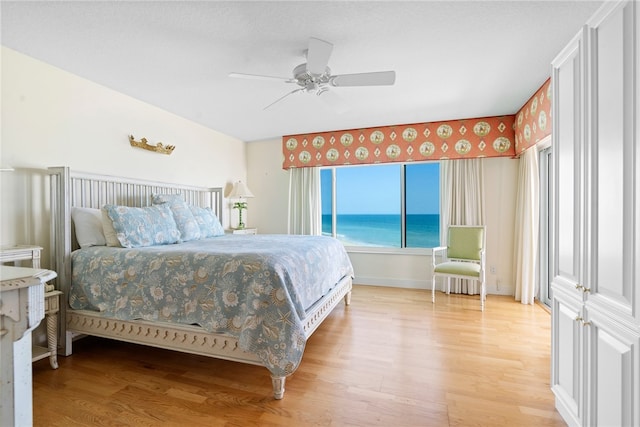 bedroom featuring a water view, hardwood / wood-style flooring, and ceiling fan