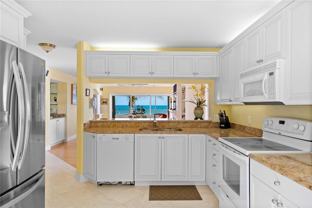 kitchen with white cabinetry, sink, white appliances, and light tile patterned floors