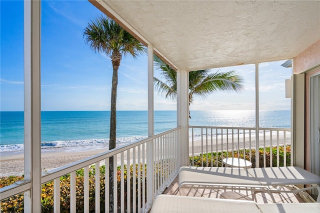 balcony featuring a beach view and a water view