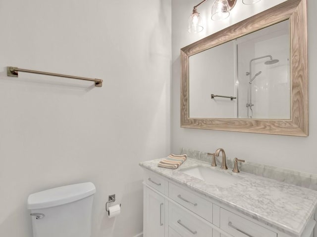 bathroom featuring toilet, a shower, and vanity