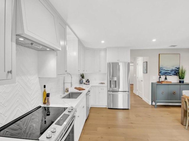 kitchen featuring light stone counters, light hardwood / wood-style floors, white cabinetry, appliances with stainless steel finishes, and sink