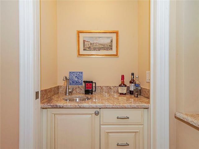 bar featuring light stone countertops and sink