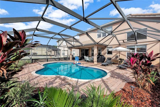 view of pool with glass enclosure and a patio area