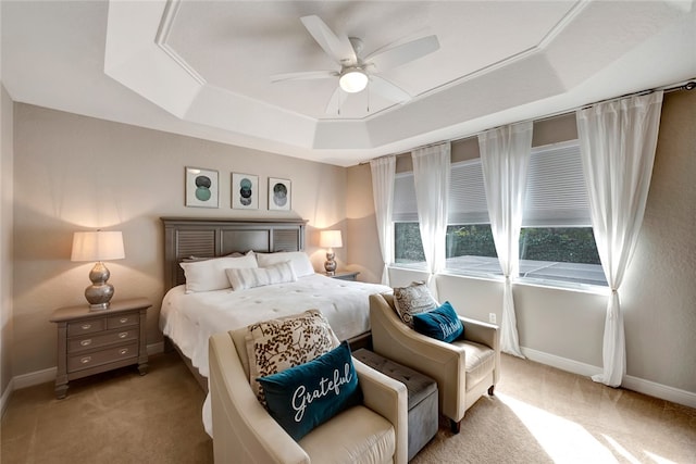 bedroom with ceiling fan, a raised ceiling, and light colored carpet