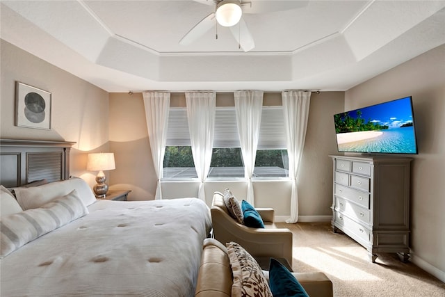 carpeted bedroom with ceiling fan and a tray ceiling