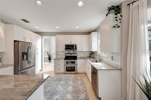 kitchen featuring white cabinets, sink, light stone counters, and appliances with stainless steel finishes