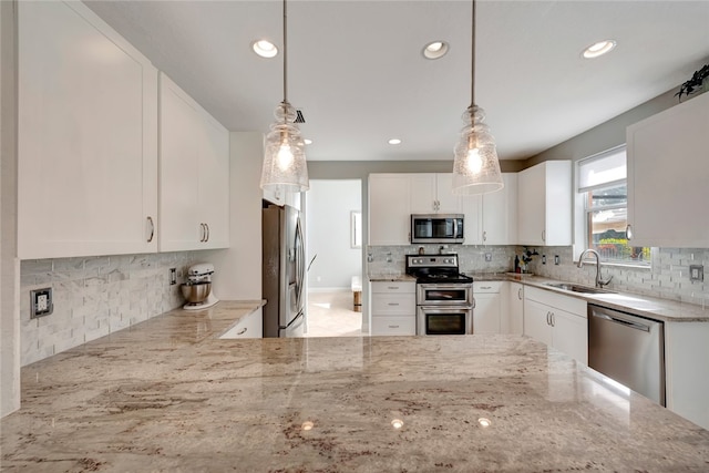 kitchen featuring pendant lighting, white cabinetry, light stone counters, and appliances with stainless steel finishes