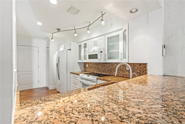 kitchen featuring crown molding, dark stone counters, white cabinetry, light tile patterned floors, and white appliances