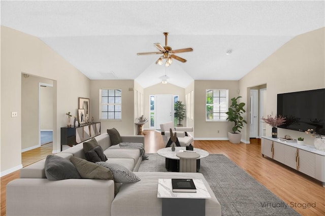 living area featuring baseboards, vaulted ceiling, and light wood finished floors