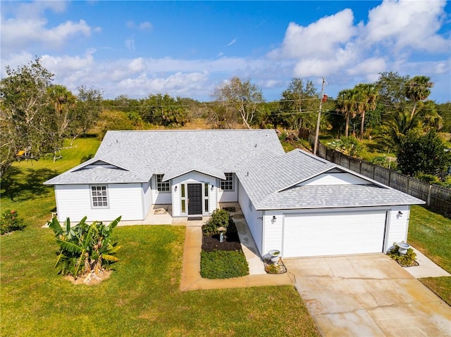 view of front of house featuring roof with shingles, fence, a garage, driveway, and a front lawn