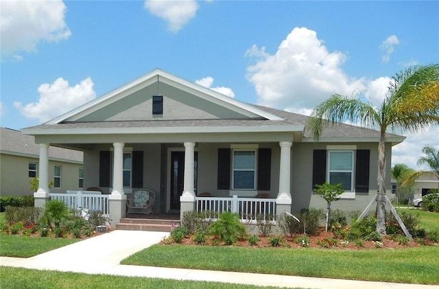 view of front of home with stucco siding, roof with shingles, and covered porch