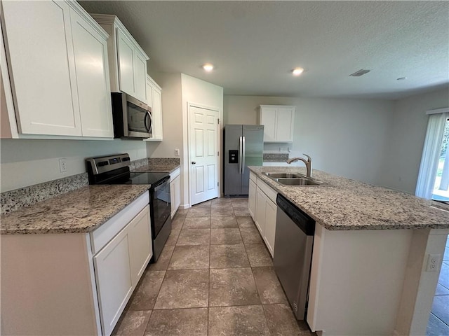 kitchen with visible vents, a center island with sink, stainless steel appliances, white cabinetry, and a sink