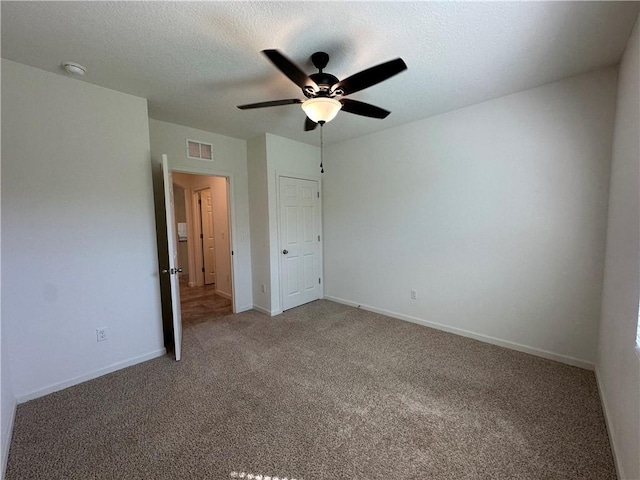 unfurnished bedroom featuring visible vents, a ceiling fan, a textured ceiling, carpet flooring, and baseboards