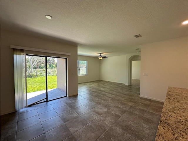 spare room with visible vents, baseboards, arched walkways, a textured ceiling, and a ceiling fan