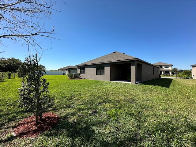 rear view of house with a yard and stucco siding