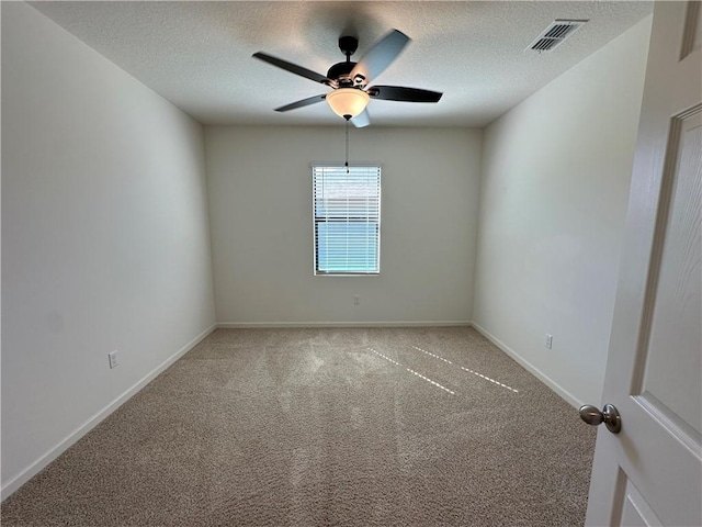 empty room with a ceiling fan, visible vents, carpet floors, and a textured ceiling