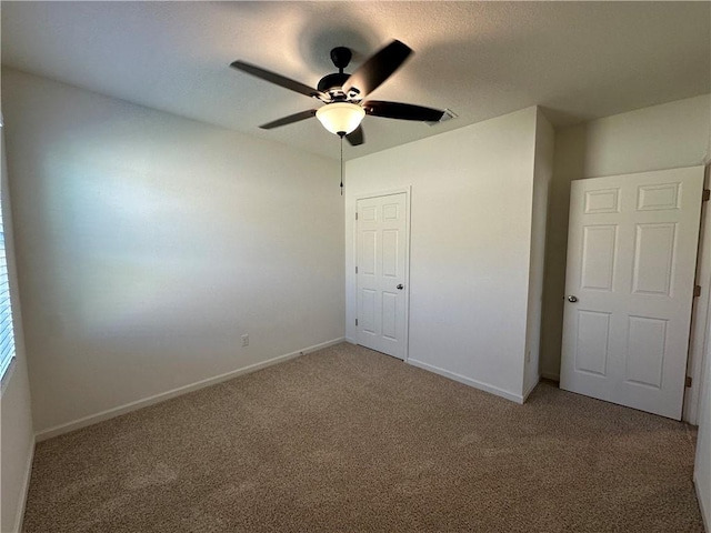 unfurnished bedroom featuring ceiling fan, baseboards, and light carpet