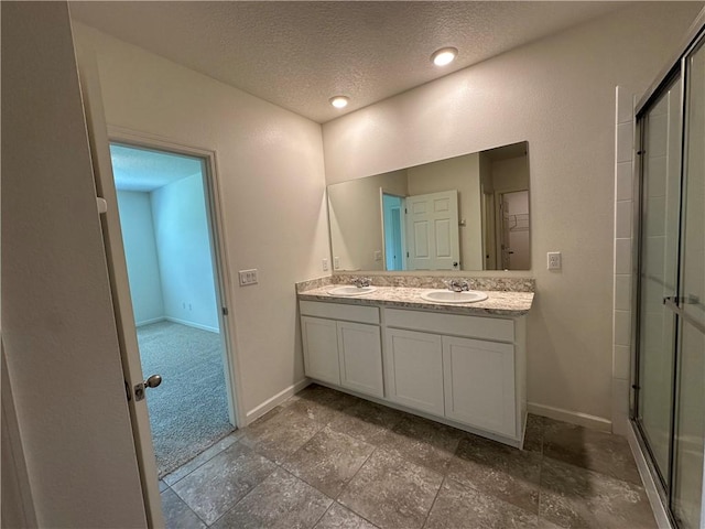 bathroom with double vanity, baseboards, a stall shower, and a sink