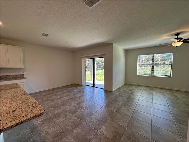 unfurnished living room with visible vents, baseboards, and a ceiling fan