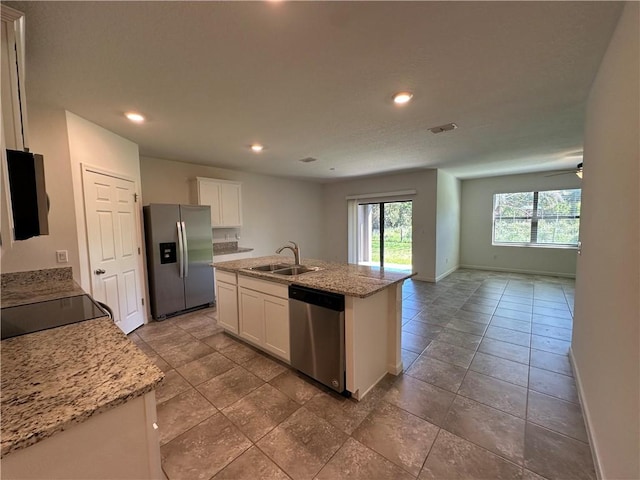 kitchen featuring baseboards, open floor plan, stainless steel appliances, white cabinetry, and a sink