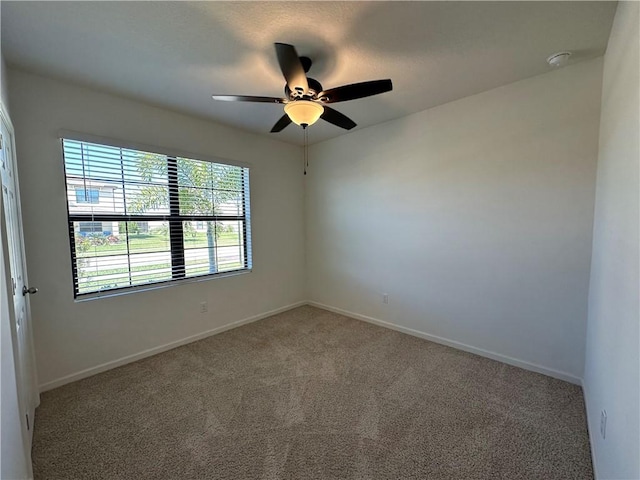 carpeted empty room featuring baseboards and ceiling fan