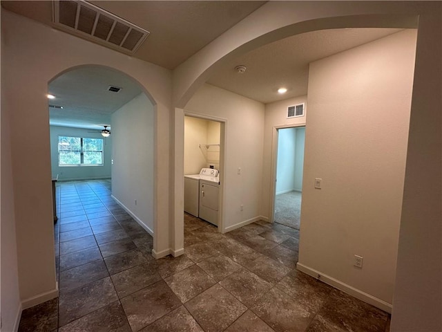 hall with visible vents, baseboards, arched walkways, and independent washer and dryer