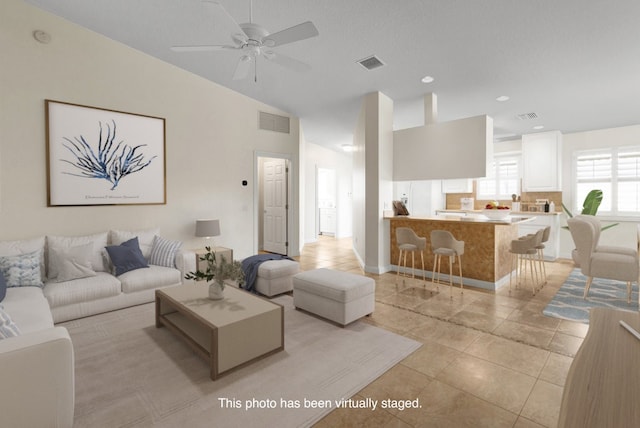 living room with vaulted ceiling, light tile patterned floors, and ceiling fan