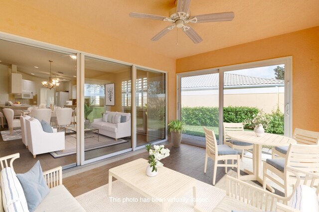 sunroom with ceiling fan with notable chandelier and plenty of natural light