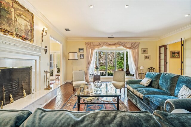 living room with hardwood / wood-style flooring, crown molding, and a fireplace