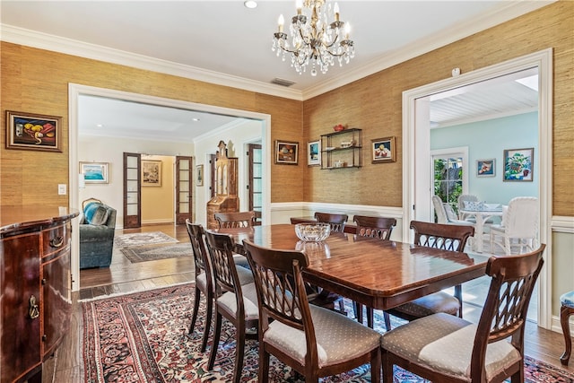 dining area with a chandelier, ornamental molding, and hardwood / wood-style flooring