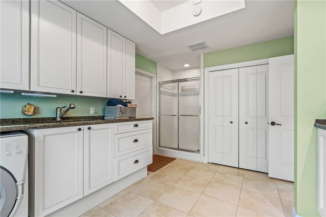 washroom with cabinets, washer / dryer, light tile patterned floors, and sink