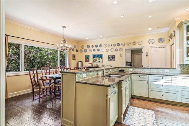 kitchen with dark stone countertops, sink, hanging light fixtures, and dark hardwood / wood-style floors