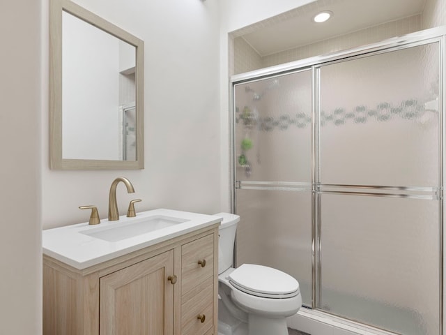 bathroom with toilet, an enclosed shower, and vanity