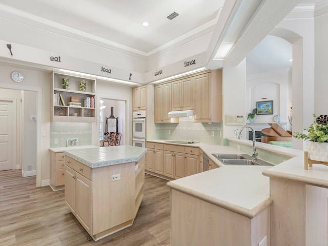 kitchen featuring kitchen peninsula, light brown cabinetry, light hardwood / wood-style floors, and a kitchen island