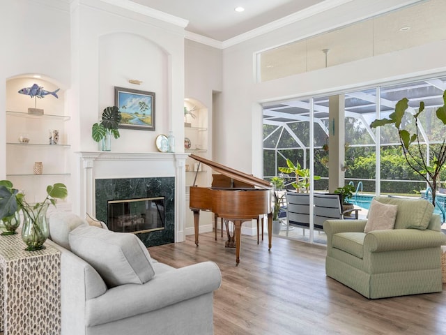 sitting room featuring a premium fireplace, wood-type flooring, a towering ceiling, and crown molding