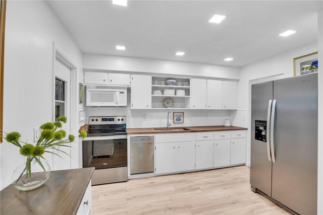 kitchen featuring wood counters, sink, light hardwood / wood-style flooring, appliances with stainless steel finishes, and white cabinets