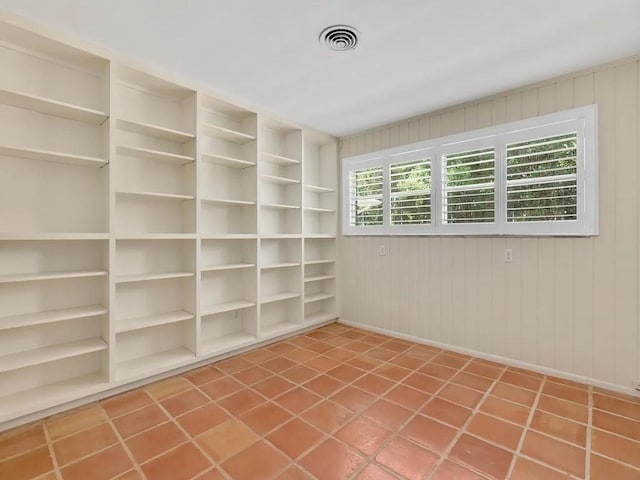 tiled spare room with built in shelves and wooden walls